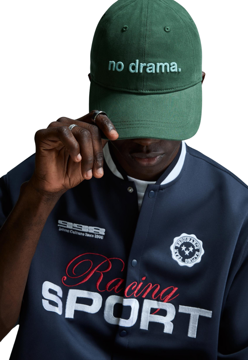 Gorra color verde olivo para hombre con un texto azul “no drama” bordado, estilo minimalista y moderno